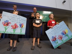 Andrew Otway, president and CEO of the Royal Alexandra Hospital Foundation, and Mike House, president and CEO of the Stollery Children's Hospital Foundation, wait to receive thank-you cards from six-year-old triplets Liam, David and Ryan Ennis during a news conference at the University of Alberta. A researcher at the Women and Children's Health Research Institute discovered a congenital heart condition in Liam when his mother was in her third trimester.