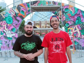 Street artists Evan Brunt, left, and AJA Louden posing in front of their Works gate on Churchill Square, The Usual Characters.