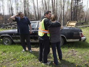 Curtis Cree comforts his wife as they inspect what is left of their cabin on the Clearwater Reserve portion of the Fort McMurray First Nation, east of Fort McMurray Alta. on Thursday June 2, 2016. Several of Cree's family's cabins, including his own, were destroyed by wildfire. Band member Bill Creedon is also pictured (left).