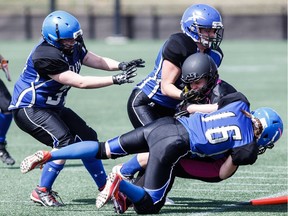 Edmonton's Jessica Anderson and Jaclyn Brewer tackle Grand Prairie's Sydney Spencer during a game between the Edmonton Storm and the Grand Prairie Anarchy at Clareview Recreation Centre in Edmonton on May 7, 2016.