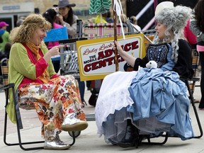 Shannan Calcutt "Lady Luck The Mobile Advice Centre" gives advice to Andrea House "Little Bo Peep" during the Edmonton International Street Performers Festival in Churchill Square.