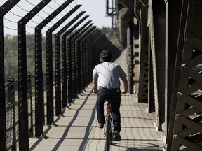 A man rides next to controversial suicide barriers on the east side of the High Level Bridge in Edmonton, on July 18, 2016.