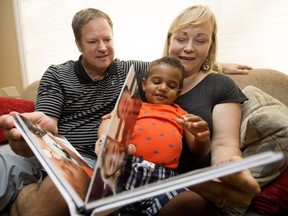 Dwayne Von Sprecken, Joanne Currie, and their son Jacob, 19-months-old, look at a family album at their home in Sherwood Park on June 27, 2016.