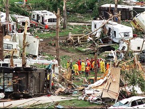 Members of a rescue party are dwarfed by the destruction of Green Acres trailer park and campground in the aftermath of the tornado that killed 12 people and injured 140 on July 16, 2000.
