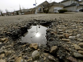 The sun is reflected in a water-filled pothole on a residential road in southwest Edmonton on April 5, 2016.