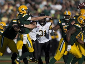 Edmonton Eskimos Mike Reilly (13) is hit on a throw by members of Hamilton Tiger-Cats during second half action at Commonwealth Stadium on Saturday, July 23, 2016 in Edmonton.