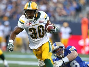 Edmonton Eskimos RB John White runs through a tackle attempt from Winnipeg Blue Bombers LB Ian Wild during CFL action in Winnipeg on July 14, 2016.