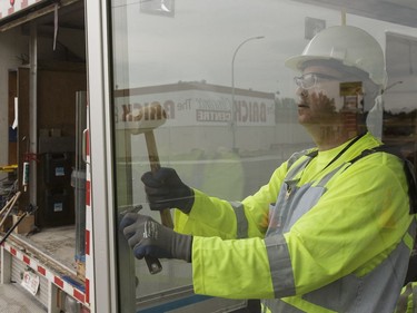 Edmonton Transit System utility worker Robert Young replaces a broken glass panel with coworker Pono Vey (not shown) at a bus shop on 107 Avenue near 120 Street in Edmonton, on Wednesday, July 20, 2016.
