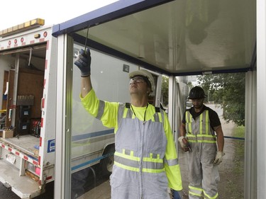 Edmonton Transit System utility workers Robert Young and Pono Vey replace a broken glass panel at a bus shop on 107 Avenue near 120 Street in Edmonton, on Wednesday, July 20, 2016.