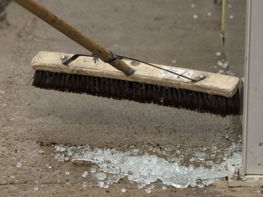 Edmonton Transit System utility worker Pono Vey sweeps up broken glass as he and coworker Robert Young replace a damaged glass panel at a bus shop on 107 Avenue near 120 Street in Edmonton, on Wednesday, July 20, 2016.