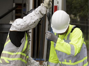 Edmonton Transit System utility workers Robert Young (right) and Pono Vey replace a broken glass panel at a bus shop on 107 Avenue near 120 Street in Edmonton, on Wednesday, July 20, 2016.