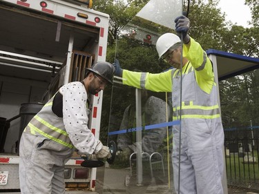 Edmonton Transit System utility workers Robert Young (right) and Pono Vey replace a broken glass panel at a bus shop on 107 Avenue near 120 Street in Edmonton, on Wednesday, July 20, 2016.
