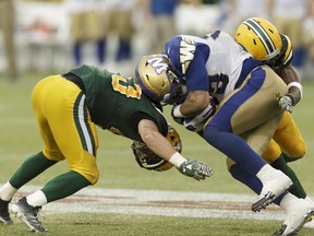 Edmonton's Neil King (43) and Winnipeg's Andrew Harris (33) collide during a CFL football game between the Edmonton Eskimos and the Winnipeg Blue Bombers at The Brick Field at Commonwealth Stadium in Edmonton, on July 28, 2016.