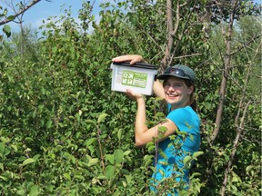 Felysia Green, EALT's Conservation Intern, triumphantly holding her geocache find at Pipestone Creek Conservation Lands.