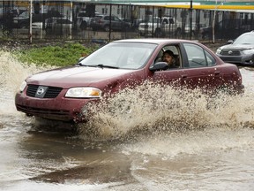 A driver drives through high water as flooding hits the area of 101 Street and 105 Avenue as a thunderstorm struck Edmonton on Friday, July 15, 2016.