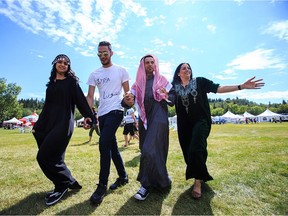 (From left) Syrian refugees Sabrin Abou Hamrah, Rani Abou Hamrah, Basel Abou Hamrah and Laila About Hamrah share a Syrian dance during the 2016 Heritage Festival in Hawrelak Park in Edmonton, Alta., on Saturday, July 30, 2016. (Codie McLachlan/Postmedia)