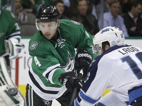 Dallas Stars defenseman Jason Demers (4) passes the puck against Winnipeg Jets left wing Andrew Ladd (16) during the first period of an NHL hockey game Tuesday, Dec. 9, 2014, in Dallas.