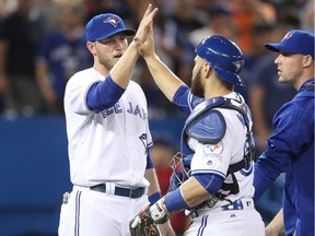 Michael Saunders (21) of the Toronto Blue Jays celebrates the team's victory with Russell Martin (55) during MLB game action against the Kansas City Royals on July 6, 2016 at Rogers Centre in Toronto.