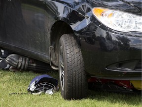 A crushed cricket helmet and other equipment can be seen jammed under a car which landed on a five-year-old boy at Edmonton's Coronation Park on Saturday, July 16, 2016. The boy was pulled to safety with no serious injuries.