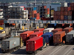 A man walks between transport trucks waiting to deliver cargo at Port Metro Vancouver's Center container facility in a May 10, 2013 file photo.