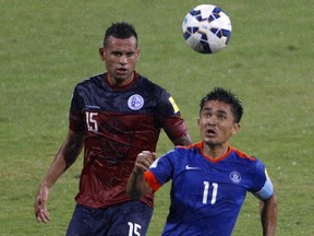 India's captain Sunil Chetri, right, and Guam's Shawn Nicklaw in action as it rains during their 2018 FIFA World Cup qualifying soccer match in Bangalore, India, Thursday, Nov. 12, 2015. India won the match 1-0.