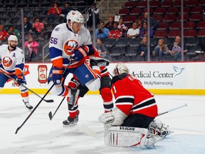 Taylor Beck #56 of the New York Islanders jumps to avoid the puck during the first period against Keith Kinkaid #1 of the New Jersey Devils at the Prudential Center on September 25, 2015 in Newark, New Jersey.