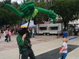A child with a balloon sword battles Phileas Flash as Phizzlewit the Fairy Finder and his sculpture Burnard the Dragon at the Edmonton Street Performers Festival at Churchill Square in Edmonton on July 11, 2016.