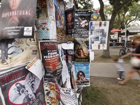 Fringers walk past theatre posters during the 2016 Edmonton Fringe Theatre Festival.