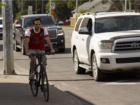 A cyclist rides on the sidewalk as traffic moves north on 109 Street near 82 Avenue on Sunday.