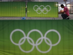 A worker fastens signage to a barrier in the Olympic Park as preparations continue for the Summer 2016 Olympics in Rio de Janeiro, Brazil, Wednesday, Aug. 3, 2016. The Summer 2016 Olympics is scheduled to open Aug. 5.