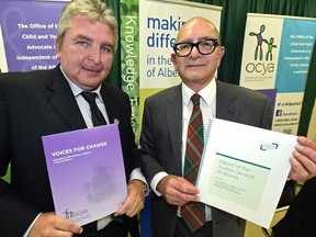 Auditor General Merwan Saher (right) and Child and Youth Advocate Del Graff (left) hold up their independent reports on the Department of Human Services' delivery of child and family services programs to Indigenous children in Alberta on July 19, 2016.