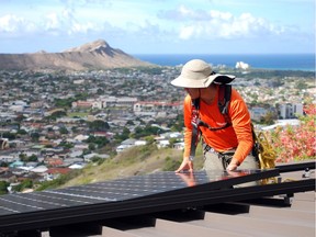 In this Friday, July 8, 2016, photo, Dane Hew Len, lead installer for RevoluSun, places a solar panel on a roof in Honolulu. Hawaii is a national leader in rooftop solar power, and the state has an ambitious goal of using only renewable energy by 2045. But people are being shut out of solar incentive programs because of limits set by the state.