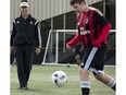 Bryan Payne (left), president of the Edmonton Minor Soccer Association North, kicks the ball around with his son Kurtis Payne, 14, in Edmonton on Aug. 8, 2016. Some soccer associations, and other groups, are concerned about a lapsed government program to cover the cost of police checks for volunteers.