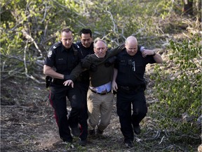 Protestor Eric Gormley is taken away by police in April from the Cloverdale footbridge where trees were cut down for the LRT Valley Line.