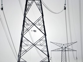 A helicopter delivers materials and tools to workers stringing up high tension power lines on giant new towers east of Clareview in Edmonton in a 2013 file photo.