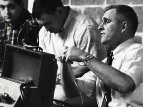 Edmonton Eskimos head coach Neill Armstrong, right, watches and discusses film with team players in 1967. Edmonton Journal file photo.