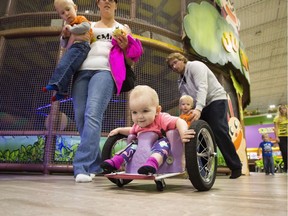 One-year-old Eva Moore plays at an indoor play ground in Edmonton Alta, on Tuesday August 9, 2016. Evelyn Moore isn't the fastest kid on the racetrack, but she's by far the tiniest. At 13-months old, the paralyzed toddler skilfully wheels her homemade wheelchair around the simulated track at Treehouse, an indoor playground in northeast Edmonton that she often visits with her mom.