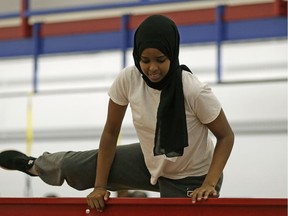 Fatuma Gelle, 17, climbs over a fence during a police training obstacle course at police headquarters in downtown Edmonton on Friday August 12, 2016.