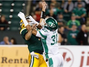 Saskatchewan Roughriders' Justin Cox (31) hits Edmonton Eskimos' quarterback Mike Reilly (13) during first half CFL football action in Edmonton on Friday, August 26, 2016.