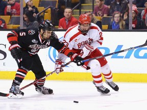 Matt Benning #5 of the Northeastern Huskies and Jakob Forsbacka Karlsson #23 of the Boston University Terriers battle for the puck during the third period at TD Garden on February 1, 2016 in Boston, Massachusetts. The Eagles defeat the Crimson 3-2.