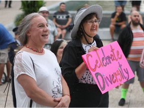 Shae Guerin, left, and Carol Breitkreutz hold a sign celebrating diversity while listening to speakers at the fifth annual Hate to Hope rally on Saturday, Aug. 6, 2016, outside the Alberta legislature in Edmonton.