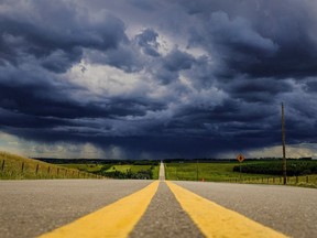 Storm clouds and the threat of hail build over a highway in southern Alberta near the town of Carstairs on Monday, July 4, 2016.