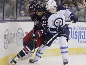 Columbus Blue Jackets' Artem Anisimov, left, and Winnipeg Jets' Jacob Trouba fight for a loose puck during the second period of an NHL hockey game Tuesday, Nov. 25, 2014, in Columbus, Ohio.