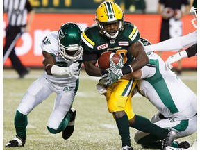 Saskatchewan Roughriders' Demetrice Morley (28) and Justin Capicciotti (7) tackle Edmonton Eskimos' Shakir Bell (33) during second half CFL football action in Edmonton on Friday, August 26, 2016.