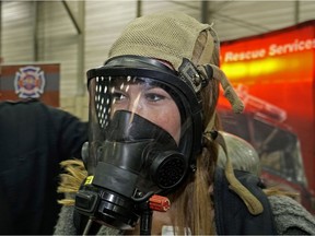 Natalie Horvat tries on a firefighter mask at the Alberta Employment and Career Fair. More than 10,000 Albertans were expected to attend the two-day event.
