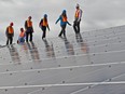 Dignitaries check out the new solar panels on the roof of the Devon Community Centre in Devon on Sept. 9, 2015. Last week's federal budget earmarked an extra $1.8 billion to expand programs that help workers upgrade their skills or start a business.