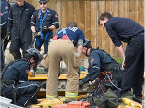 Firefighters with a worker who was killed when a trench collapsed at 107 Avenue and 123 Street in Edmonton on April 28, 2015.