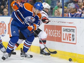 Edmonton Oilers defenceman Oscar Klefbom (77) and New Jersey Devils Bobby Farnham (23) fight for the puck during NHL action at Rexall Place in Edmonton on November 20, 2015.