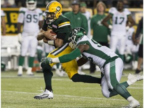 The Edmonton Eskimos' quarterback Mike Reilly (13) is tackled by the Saskatchewan Roughriders' Ese Mrabure (98) during second half CFL action at Commonwealth Stadium, in Edmonton on Friday Aug. 26, 2016.