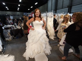 Kendal Eyben, from Vermillion, tries on bridal gowns at the Brides International booth during Bridal Fantasy at the Edmonton Expo Centre.